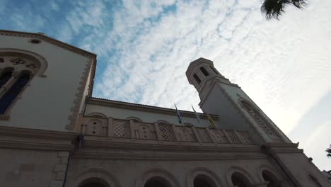 Ground-up-view-of-Agia-Napa-Cathedral-lateral-facade-under-summer-cloudy-sky---Wide-low-angle-panning-shot