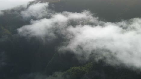 Flying-above-the-clouds-over-a-green-mountain