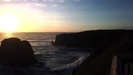 Lighthouse-on-rocky-Oregon-Pacific-coast-at-sunset,-clifftop-seascape-view