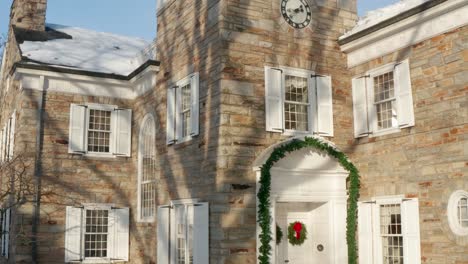 College-administration-office-building-covered-in-winter-snow-and-decorated-with-Christmas-wreath-and-garland