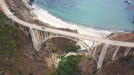 Aerial-backward-reveal-from-seaside-cliff-to-Bixby-Bridge-and-car-traffic