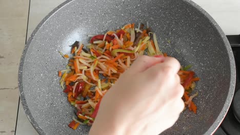 Woman's-hand-stirring-chopped-vegetables-frying-in-a-wok