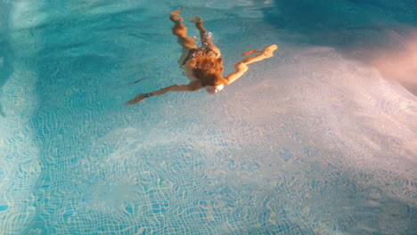 Slow-motion-shot-of-a-young-woman-swimming-inside-of-a-pool-by-herself-at-night
