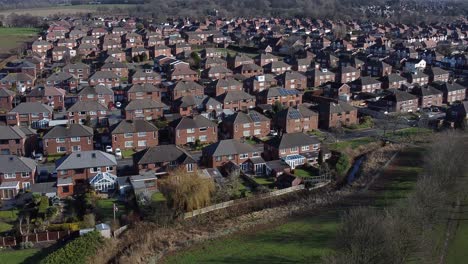 Typical-Suburban-village-Anglesey-residential-neighbourhood-property-rooftops-aerial-view-low-dolly-right