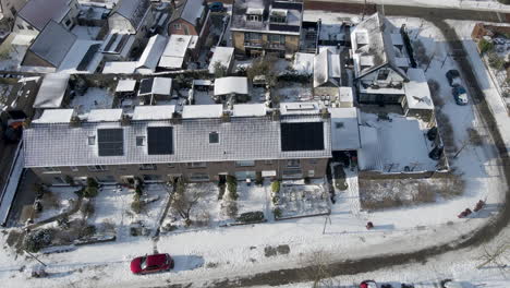 Aerial-jib-down-of-solar-panels-of-snow-covered-rooftops