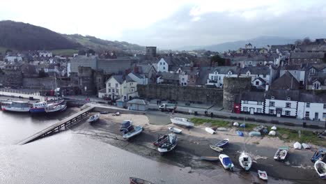 Picturesque-Welsh-Conwy-castle-and-harbour-fishing-town-boats-on-coastal-waterfront-aerial-slow-left-dolly