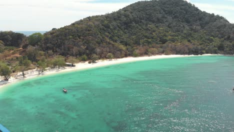 Golden-sandy-beach-sidelining-emerald-shallow-waters-of-Banana-Beach,-Koh-Hey-,-Thailand---Aerial-Fly-over-panoramic-shot
