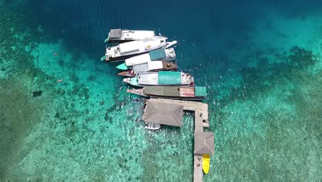 Top-view-boats-at-pier-on-paradise-island-at-tropical-destination-in-Labuan-Bajo,-Indonesia
