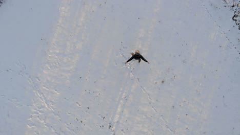 Top-down-shot-of-a-happy-person-spinning-and-dancing-the-arms-and-legs-in-the-freshly-fallen-snow-during-winter