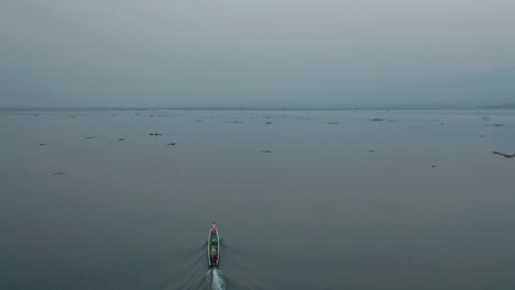 Early-morning-at-Inle-Lake-of-Myanmar-with-long-boat-on-the-move,-aerial