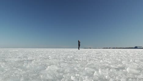Female-standing-on-frozen-surface-of-sea,-wide-view