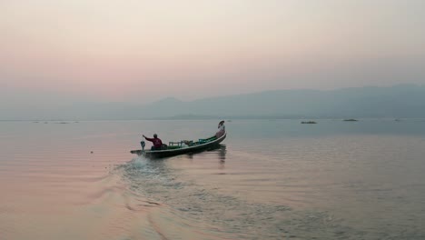 Female-tourist-sits-on-bow-of-narrowboat-on-Inle-Lake-during-beautiful-sunrise