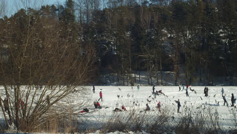 Picturesque-view-of-crowd-of-people-ice-skating,-enjoying-Frozen-Lhotka-lake-in-Harasov,-Kokorin,-Czech-Republic---Wide-slow-motion-panning-shot