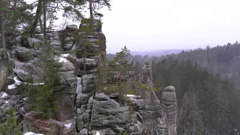 sandstone-rock-formation-with-snow-and-landscape-in-Prachov-Rocks,-Bohemian-Paradise,-pan-right