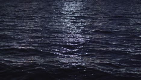 Ocean-waves-going-back-and-forth-at-night,-illuminated-by-moonlight
