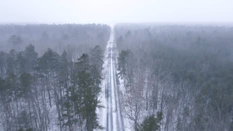 Amazing-View-Of-Snow-Covered-Road-And-Forest-Landscape-Amidst-A-Snowy-Winter-Day---aerial-shot