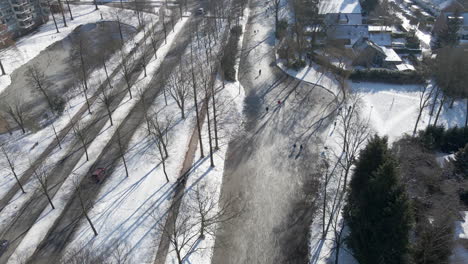 Luftaufnahme-Von-Menschen,-Die-Auf-Einem-Zugefrorenen-Fluss-In-Einer-Kleinen-Holländischen-Stadt-In-Den-Niederlanden-Eislaufen