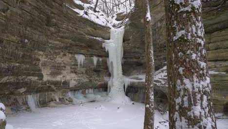 Small-frozen-waterfall-on-rocky-cliff-with-tree-in-foreground