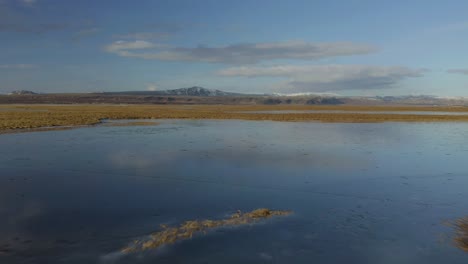 Fly-Over-Scenery-Of-Wetlands-With-Distant-Mountain-In-Background-At-Olfusa-River-Near-Selfoss-In-South-Iceland