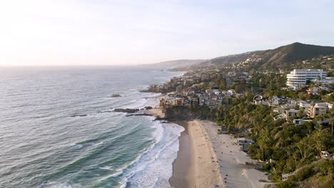 An-aerial-drone-shot-of-Thousand-Steps-Beach,-Laguna---California-with-mountain-in-the-distance-during-sunset