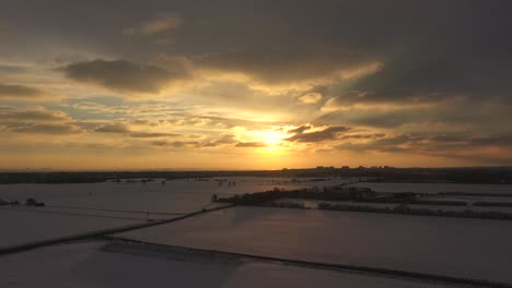 Aerial-sunset-rising-shot-with-dark-shaded-snow-fields-below