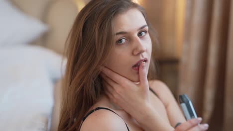 Portrait-of-a-sexy-girl-smoking-an-electron-cigarette-and-patting-her-face