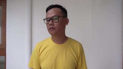 Portrait-of-casual-man-smiling-confidence-wearing-yellow-tees-and-glasses