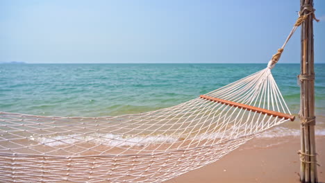 Empty-hammock-on-exotic-beach-with-sea-in-background