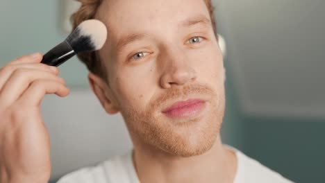close-up-portrait-of-a-handsome-blond-man-applies-face-powder