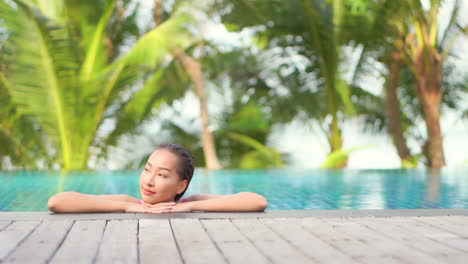 Schöne-Asiatische-Frau,-Die-Sich-Allein-Im-Pool-Entspannt-Und-In-Die-Kamera-Schaut