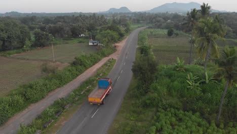 Aerial-tracking-shot-of-driving-truck-on-indian-road-during-cloudy-day