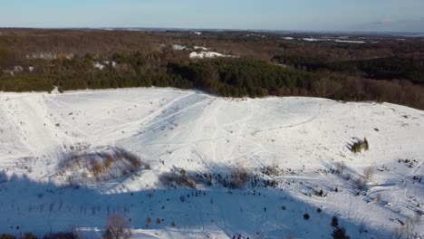 Wide-drone-shot-circling-snow-covered-outdoor-recreational-hill-park
