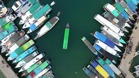 Aerial-view-above-a-lot-of-fishing-boats,-at-the-Labuan-Bajo-harbor,-island-of-Flores-in-the-Nusa-Tenggara-region-of-east-Indonesia---Rising,-top-down,-drone-shot