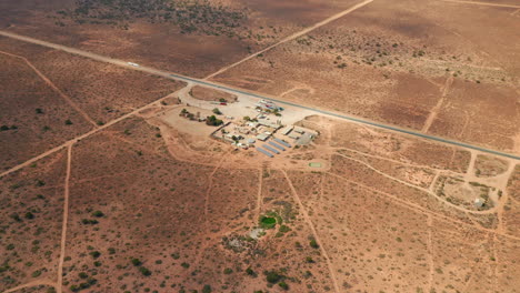 Aerial-view-of-a-self-sufficient-gas-station,-powered-by-solar-power-cells,-in-Australian-outback---pull-back,-drone-shot