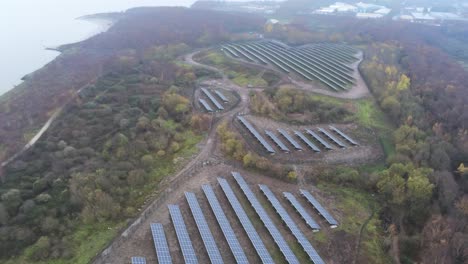 Solar-panel-array-rows-aerial-view-misty-autumn-woodland-countryside-high-orbit-right