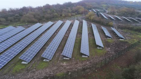 Solar-panel-array-rows-aerial-view-misty-autumn-woodland-countryside-low-slow-left-dolly