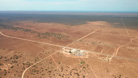 Aerial-view-overlooking-a-remote-petrol-station-with-solar-panels,-in-middle-of-wasteland,-in-Australia---approaching,-drone-shot