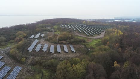 Solar-panel-array-rows-aerial-view-misty-autumn-woodland-countryside-rising