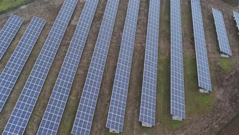 Solar-panel-array-rows-aerial-view-misty-autumn-woodland-countryside-close-birdseye-rising-tilt-up