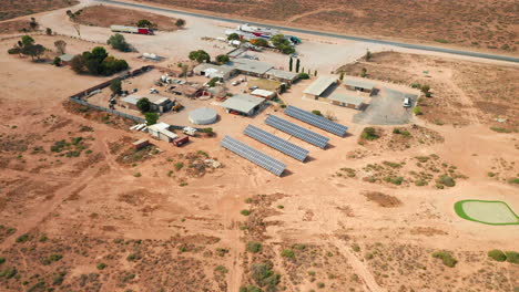 Aerial-view-of-a-distant-roadhouse-with-solar-power-cells,-in-the-Australian-Outback---pull-back,-drone-shot