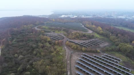 Solar-panel-array-rows-aerial-view-misty-autumn-woodland-countryside-rising-high-shot