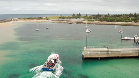 Aerial-view-of-a-ferry-arriving,-at-a-dock-on-the-Seal-island,-cloudy-day,-in-Australia---tracking,-drone-shot