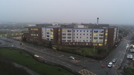 Misty-foggy-hospital-building-UK-town-traffic-aerial-view-low-angle-orbit-right