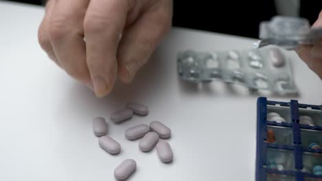 Man-taking-out-medicine-tablets-from-the-blister-pack-unto-a-table---Close-up