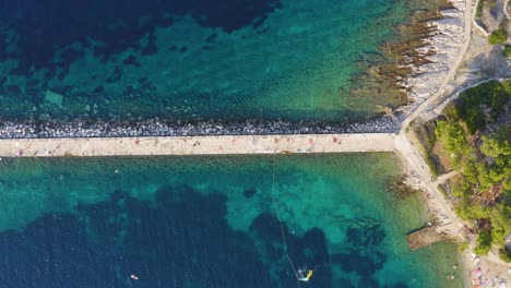 Top-down-aerial-shot-of-a-pier-on-the-outskirts-of-Veli-Losinj,-Croatia-on-a-bright-day
