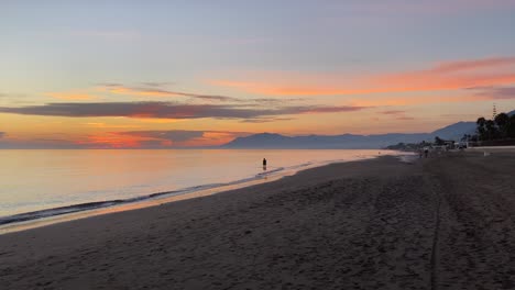 Silhouette-Einer-Person-Im-Wasser-Am-Strand-Von-Marbella,-Traumurlaubsort-Bei-Sonnenuntergang-4k-Aufnahmen