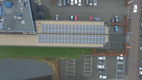Top-down-aerial-of-solar-panels-on-office-building-rooftop---drone-lifting-up