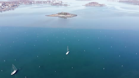 Drone-aerial-view-of-a-foggy-harbor-with-sailboats-and-islands-and-the-surrounding-shoreline