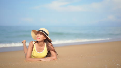 While-reclining-on-the-beach,-a-pretty-young-woman-enjoys-the-sun-and-surf