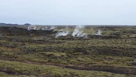 Steam-rises-from-Icelandic-geysers-in-wild-geothermal-terrain,-aerial